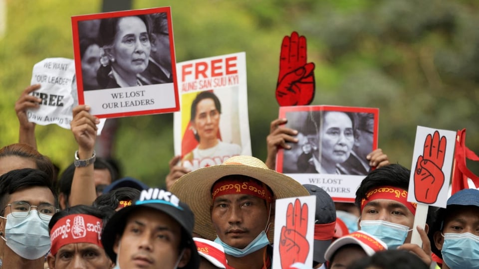 Menschen demonstrieren mit Bild von Aung San Suu Kyi.
