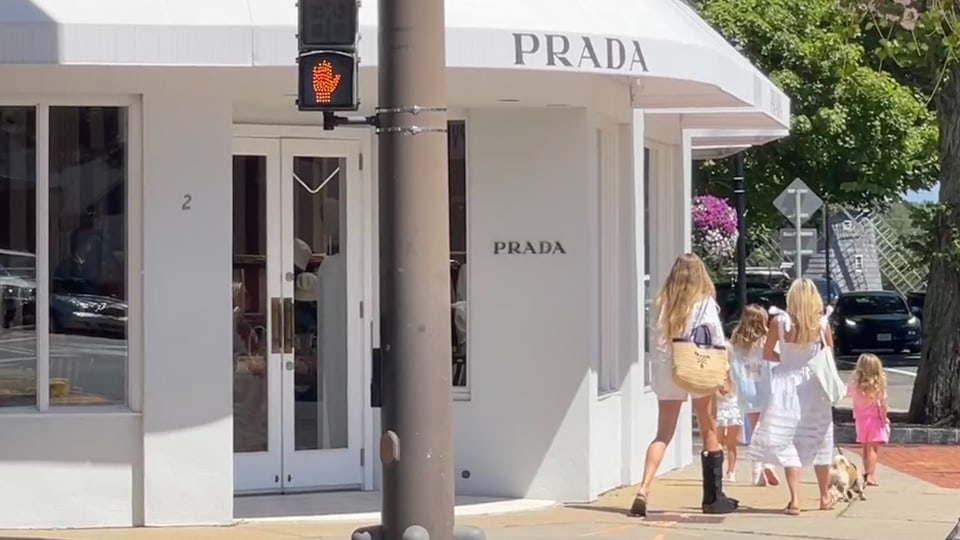 ein Prada Laden, davor Passanten in schicken Kleidern