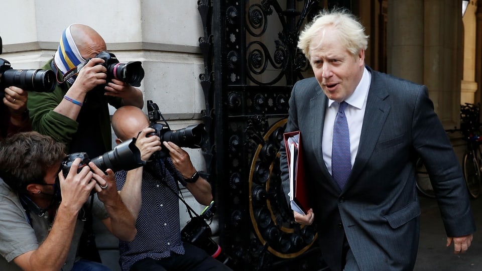 Johnson mit Mappe unter dem Arm, zahlreiche Fotografen säumen seinen Weg.