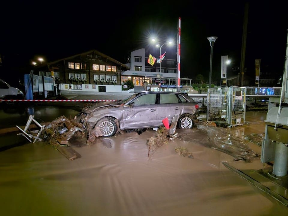 Auto im Hochwasser an Bahnübergang bei Nacht.