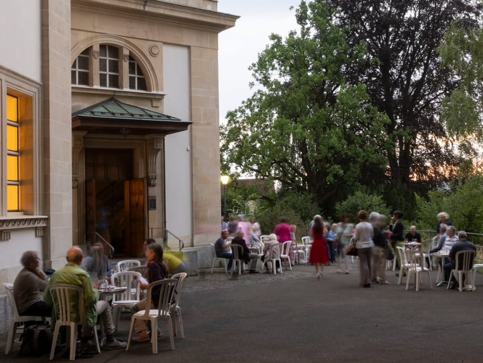 Menschen sitzen an Tischen draussen vor der Kirche zusammen, jeweils für sieben Minuten.