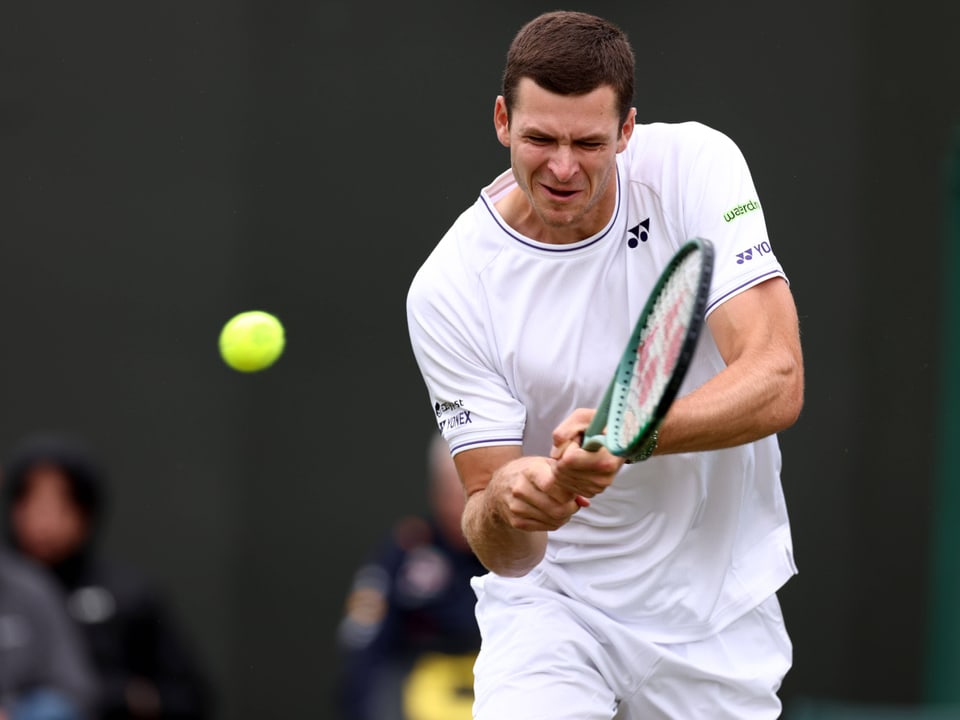 Tennisspieler schlägt Ball mit Schläger.