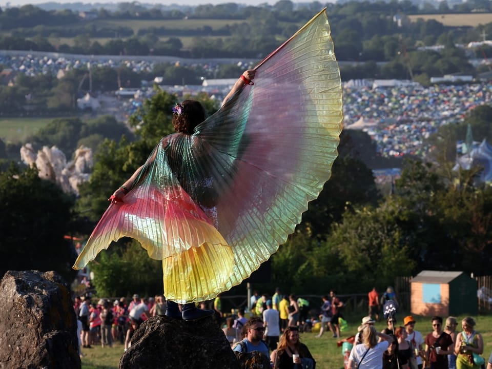 Eine Festivalbesucherin steht auf einem Steinkreis am Glastonbury-Musikfestival.