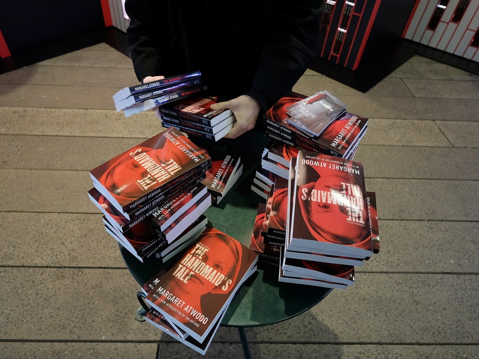 Person arrangiert Bücher auf einem Tisch.