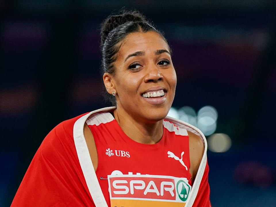 Lächelnde Sportlerin bei einem Wettkampf mit einem roten Trikot.