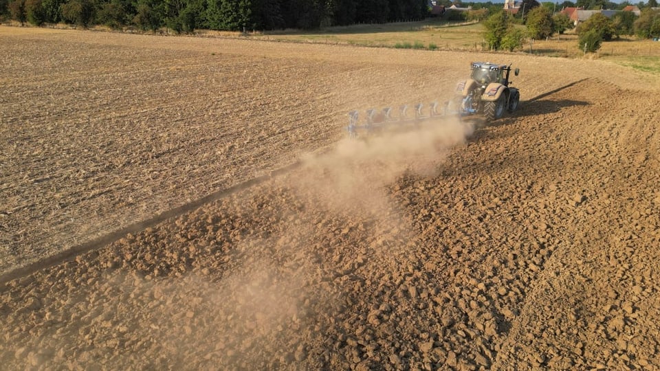 Ein Traktor pflügt durch ein trockenes Feld