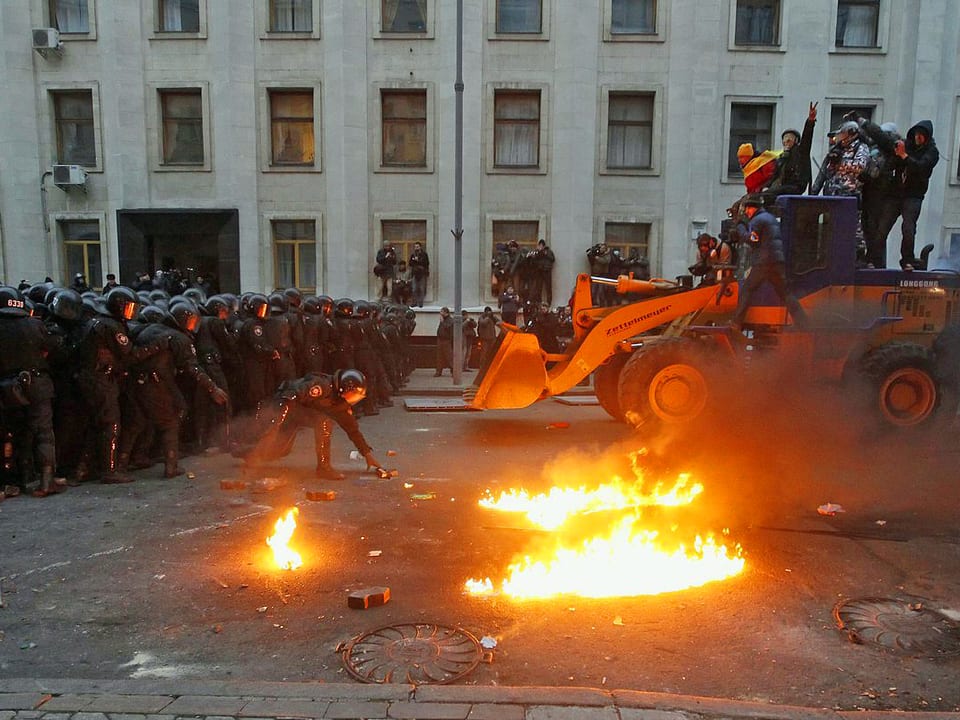 Demonstranten auf Bulldozer vor Polizeikordon.