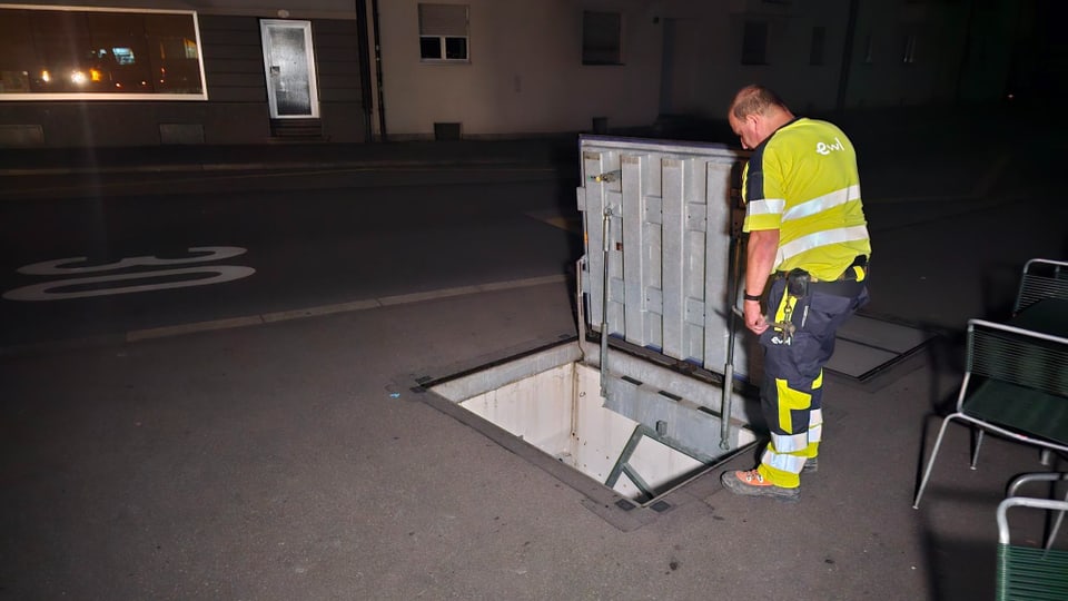 Ein Mitarbeiter von Energie Wasser Luzern EWL steht vor einem Niedergang auf einer Strasse.