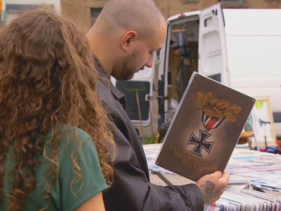 Zwei Personen schauen sich ein Buch auf einem Markt an.