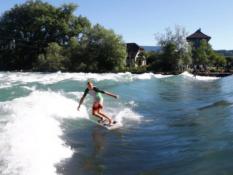 Person surft auf einer stehenden Welle in einem Fluss.