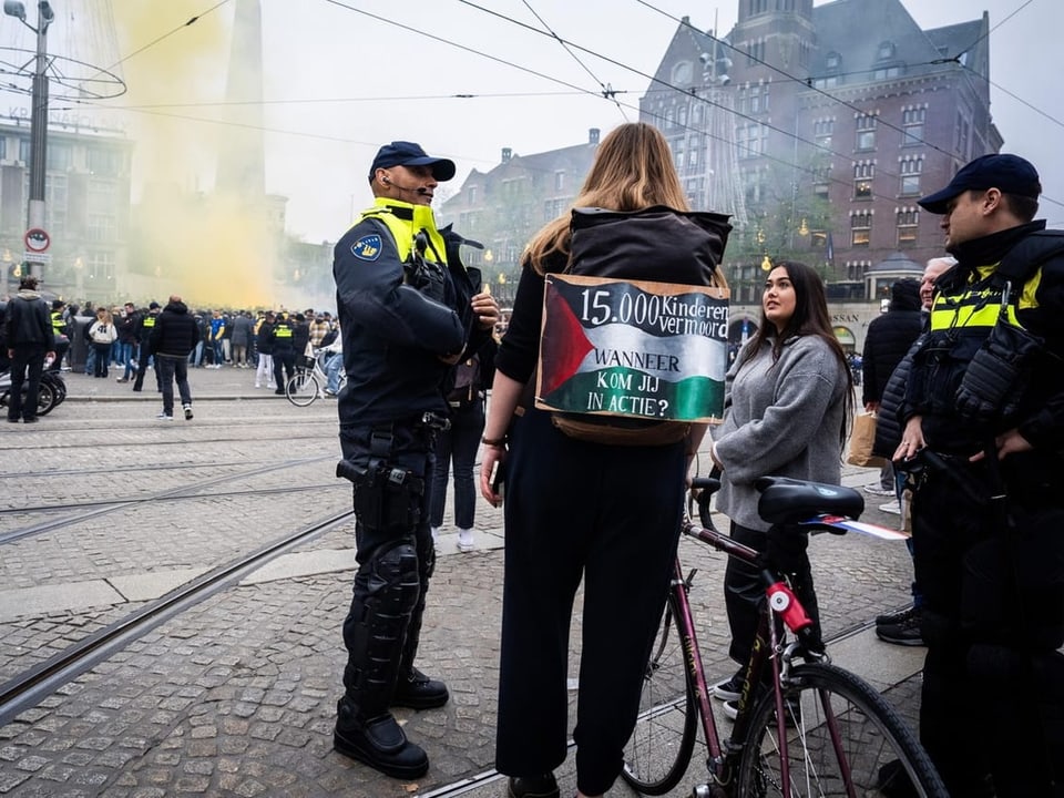 Menschen bei einer Protestaktion auf einer Stadtstrasse, umgeben von Polizeibeamten.