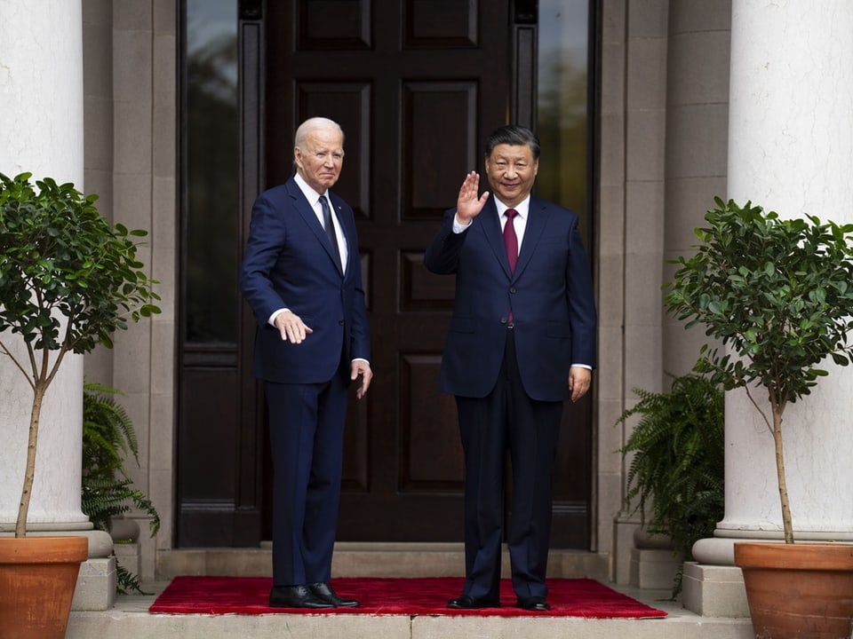 Joe Biden und Xi Jinping winken vor Hauseingang den Kameras zu.