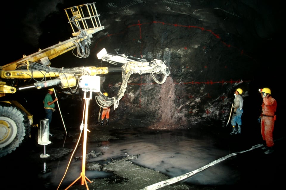 Arbeiter in einem beleuchteten Tunnel mit grosser Maschine.