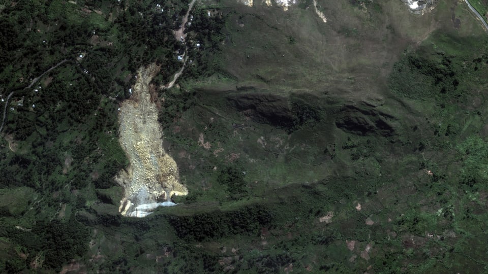 Satellitenbild eines Erdrutsches in einem grünen bewaldeten Gebiet.