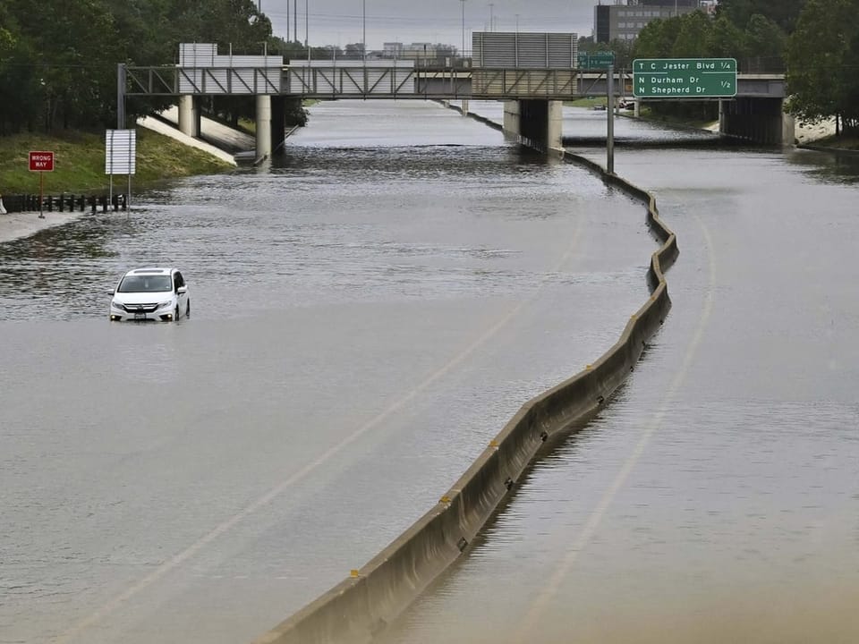 Ein Auto steht alleine auf der Autobahn, die überflutet wurde. 