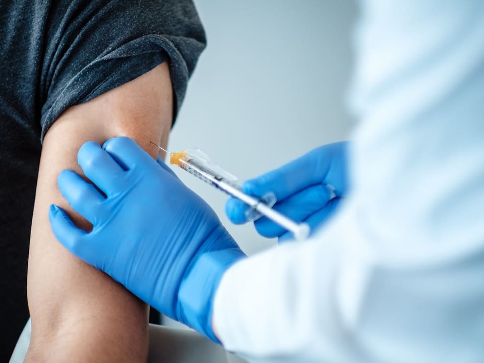 The doctor injects the vaccine into the patient's hand.