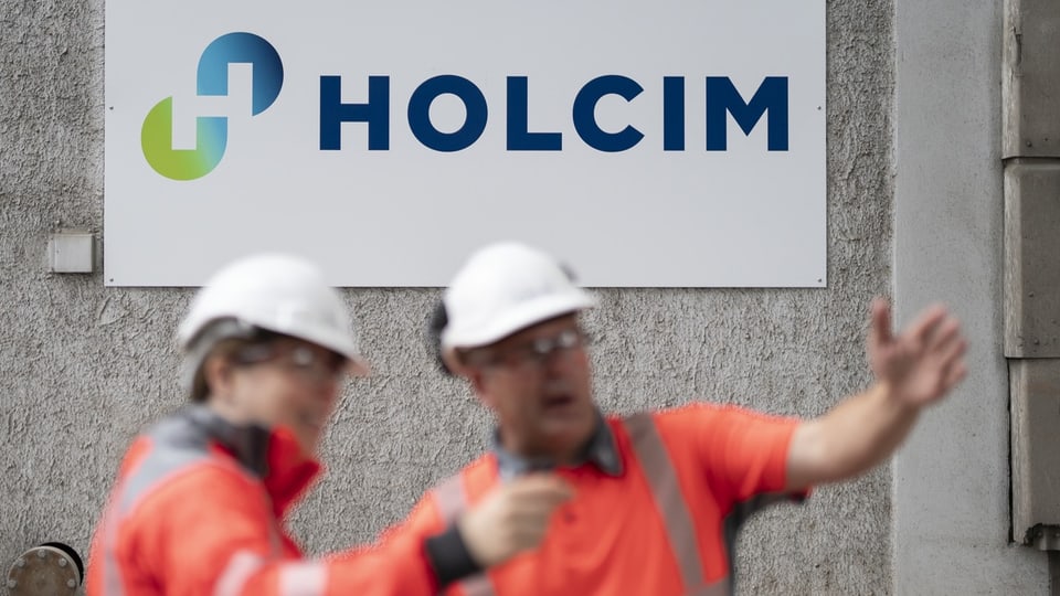 Zwei Mitarbeiter mit Helm und Schutzbrille sprechen miteinander auf dem Gelände des Holcim-Zementwerks Siggenthal.