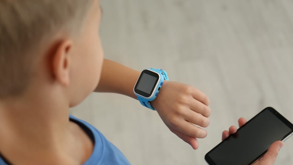 Kind mit Smartwatch und Smartphone