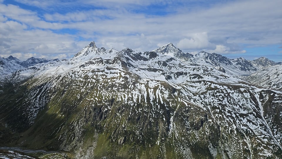 Schneebedeckte Bergkette unter bewölktem Himmel.