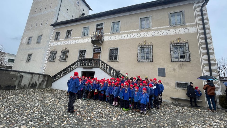 Kinder in Chalandamarz-Outfit vor einem Gebäude.