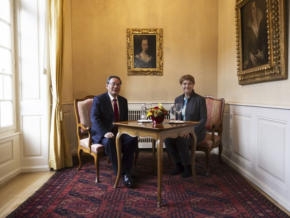 in einem Raum mit goldenen Bildern an der Wand sitzen links Mann, rechts Frau auf Lehnstühlen