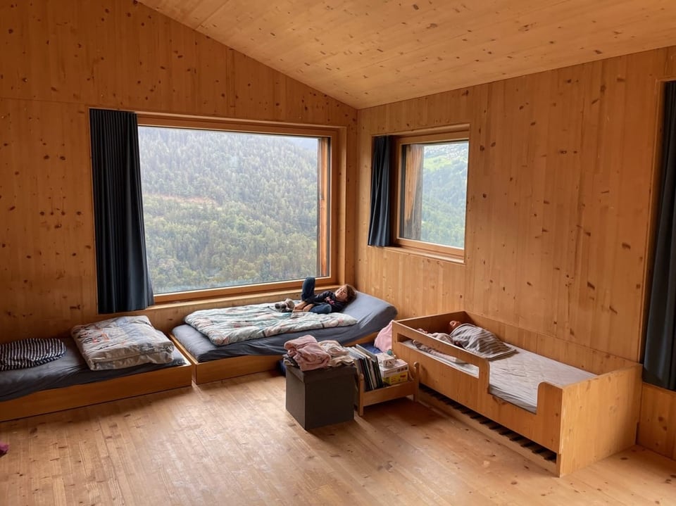 Ein Zimmer mit mehreren Betten und Vorhängen sowie viel Holz.