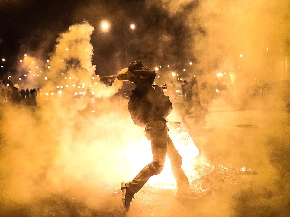 Ein Mann wirft in Lima einen Wurfkörper gegen die Polizei.