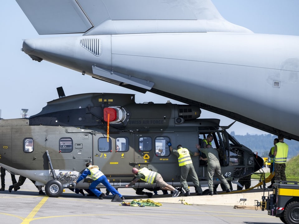 Flugzeugcrew lädt Militärhubschrauber in Cargoflugzeug.