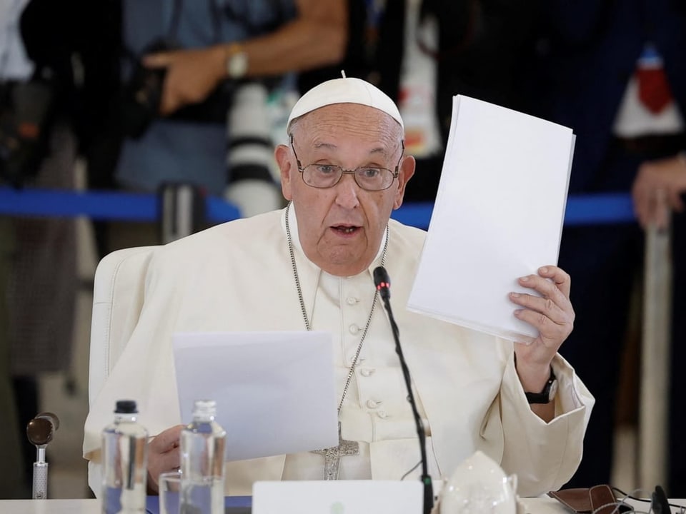 The Pope speaks with documents at the conference.