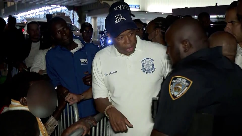 Mann mit Dächlikappe spricht mit Polizist an einer Ankunftsstelle von Flüchtenden.
