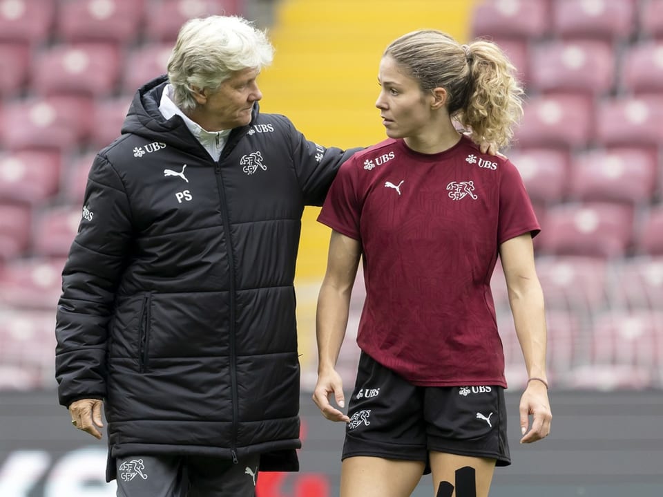 Trainer spricht mit Fussballspielerin auf dem Spielfeld.