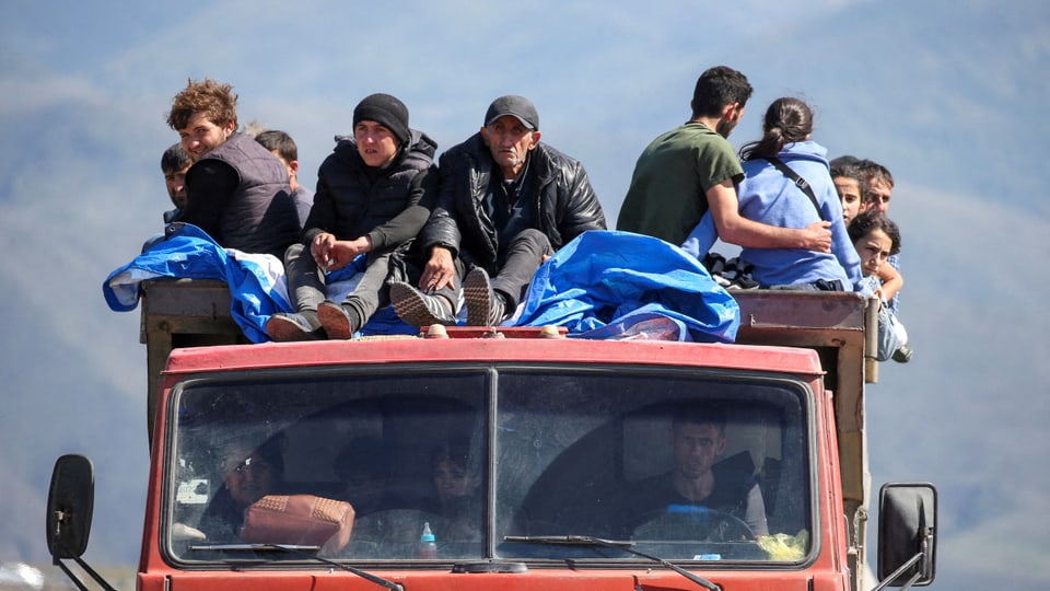Männer, Frauen und Kinder auf einem Lastwagen auf der Flucht