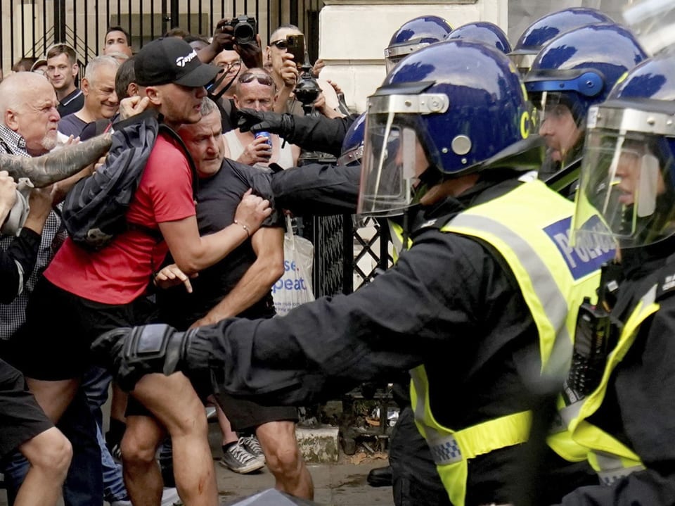 Demonstranten konfrontieren Polizisten in Schutzkleidung.