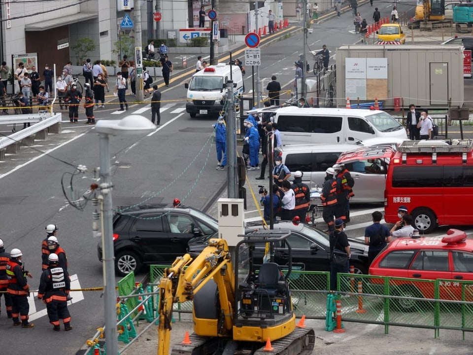 Polizei- und Krankenwagen stehen auf einer Strasse in Nara, Einsatzkräfte laufen herum.