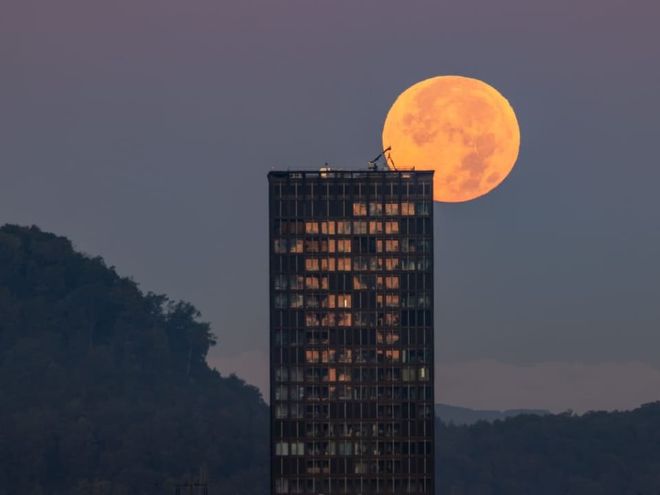 Vollmond hinter einem hohen Gebäude.