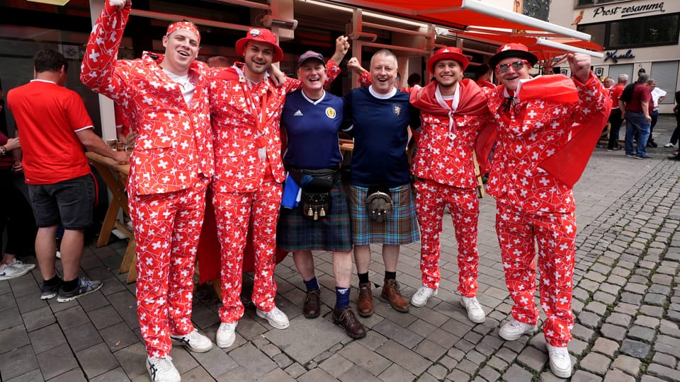 2 Schottland-Fans umgeben von 4 Schweizer Fans.