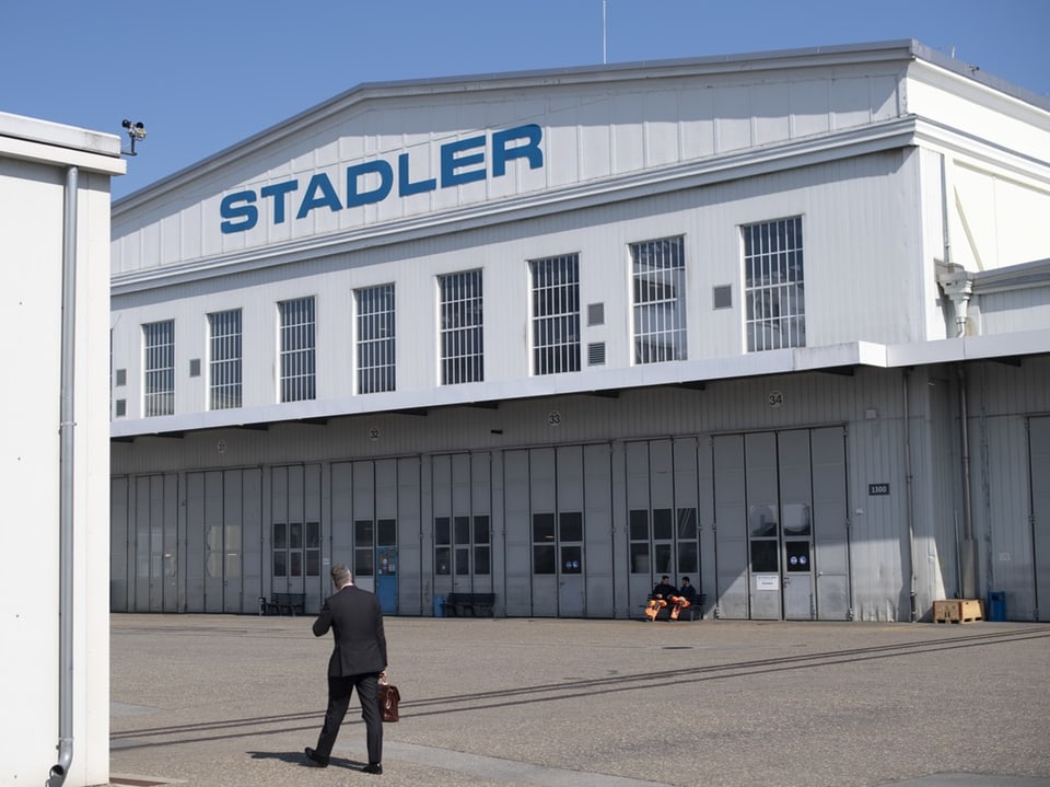 Person geht auf Stadler-Gebäude zu.