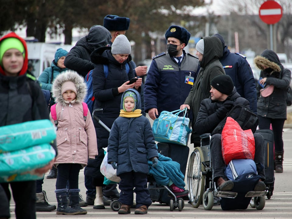 Menschen, darunter Kinder, sprechen mit einem rumänischen Grenzwart.