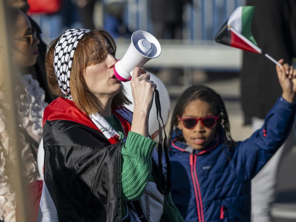 Frau mit Megafon und Kind mit Flagge bei Protest.