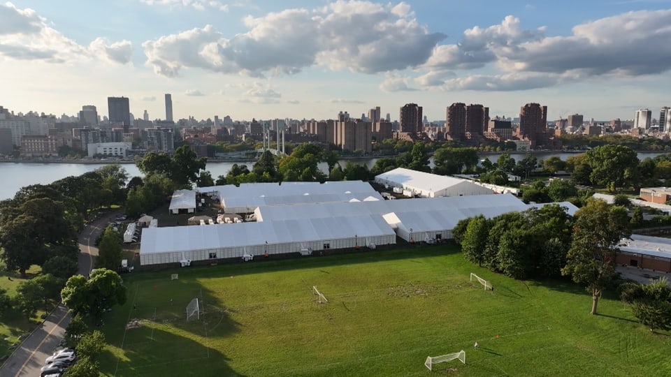Weisse lange Zelte auf Sportplätzen auf einer Insel vor Manhattan