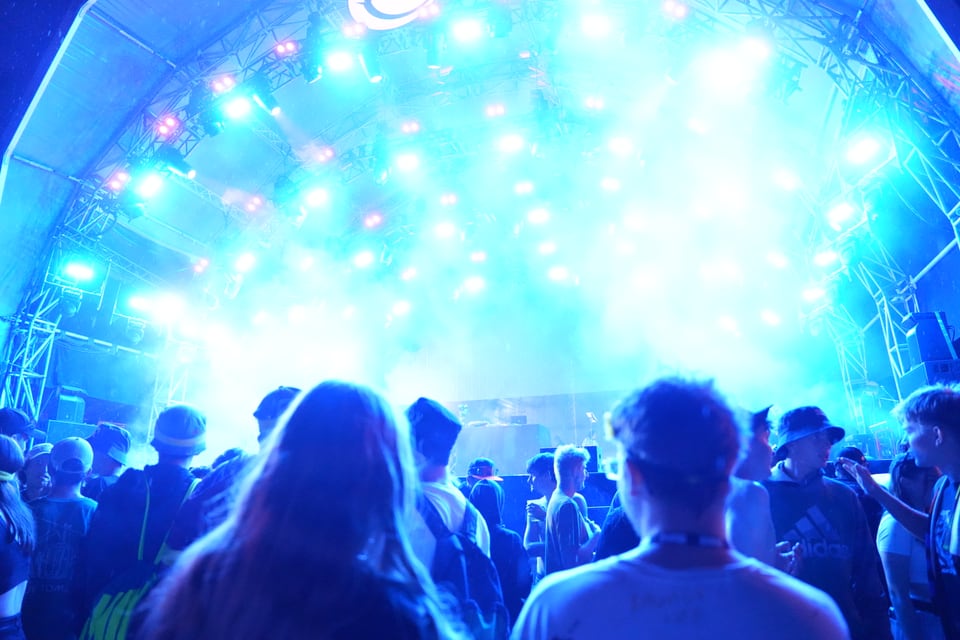 Menschenmenge bei einem Konzert unter blauer Beleuchtung am Open Air Lumnezia 2024.