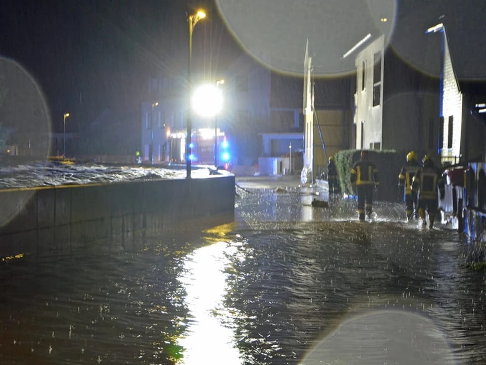 Einsatzkräfte bei Hochwasser in einer überfluteten Strasse in der Nacht.