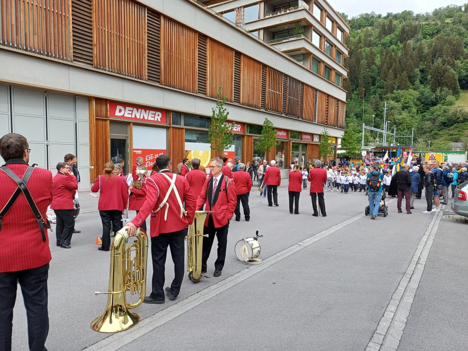 Eine Blaskapelle spielt in roten Uniformen vor einem Geschäft.