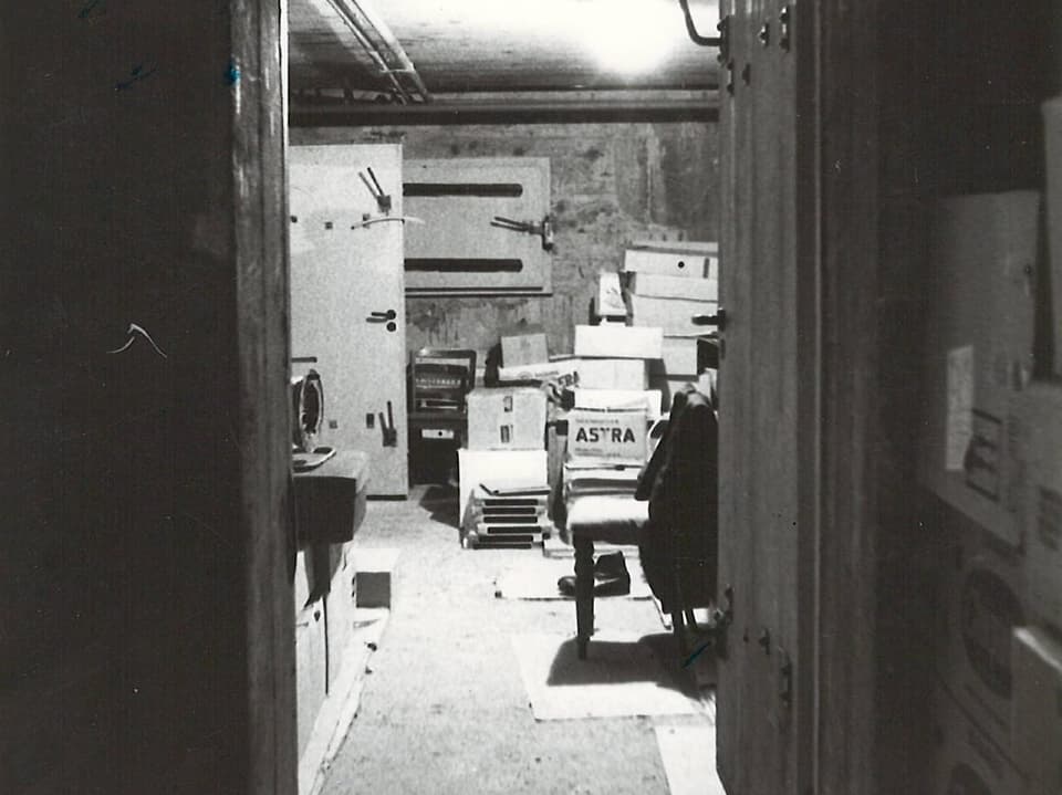 Schwarz-Weiss-Foto eines Lagerraums mit Kartons und Möbeln.