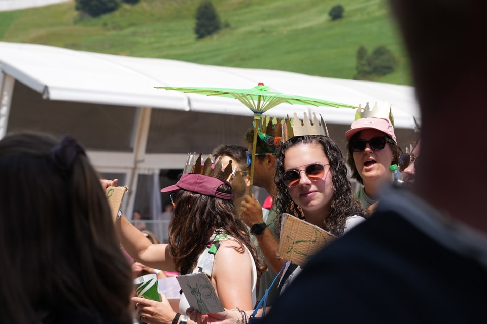 Menschenmenge auf einem Outdoor-Event mit Papierkronen.