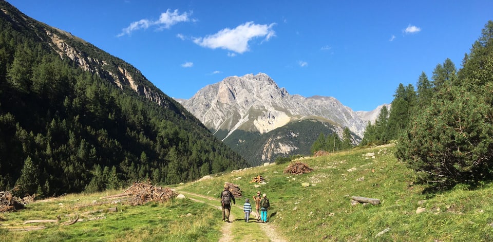 Ein Jäger und Kinder, bei schönem Wetter unterwegs in einer Bergwelt.