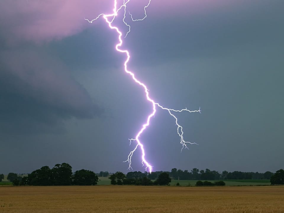Blitzschlag über einem ländlichen Feld.