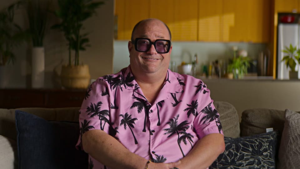 Ein übergewichtiger Mann mit grosser Brille und Hawaii-Hemd.