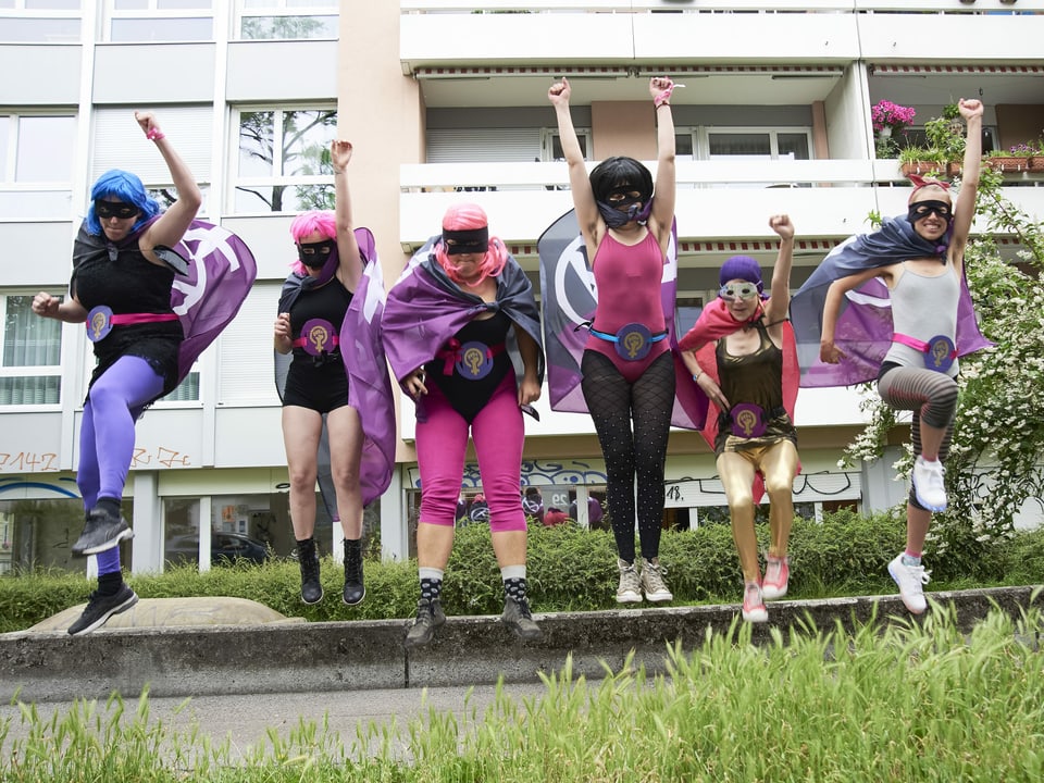 Eine Gruppe Mädchen in Superheldinnen-Kostümen springt in die Luft.