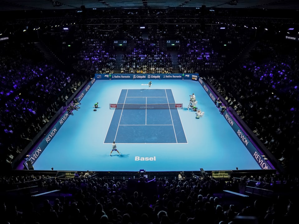 Tennismatch in einer grossen, beleuchteten Arena.